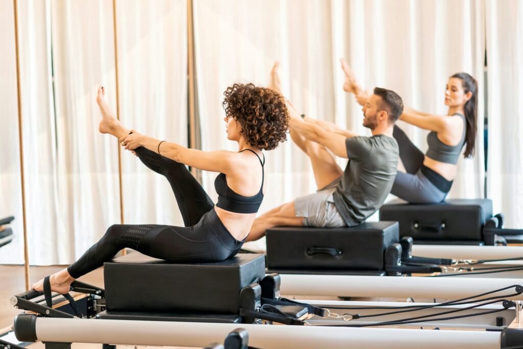 Class of group stretching legs on pilates reformer